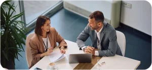 Businesswoman and male advisor discussing insurance documents at office desk, JVRC professional consultation