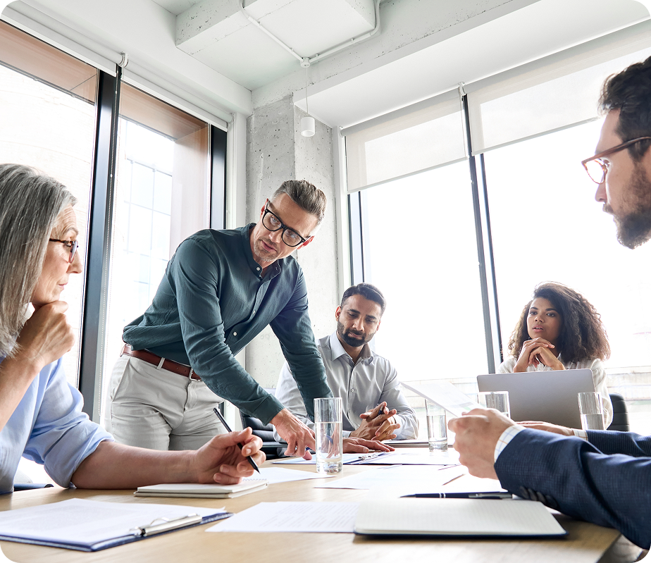 JVRC team in strategic meeting around conference table with laptops and documents, insurance solutions discussion