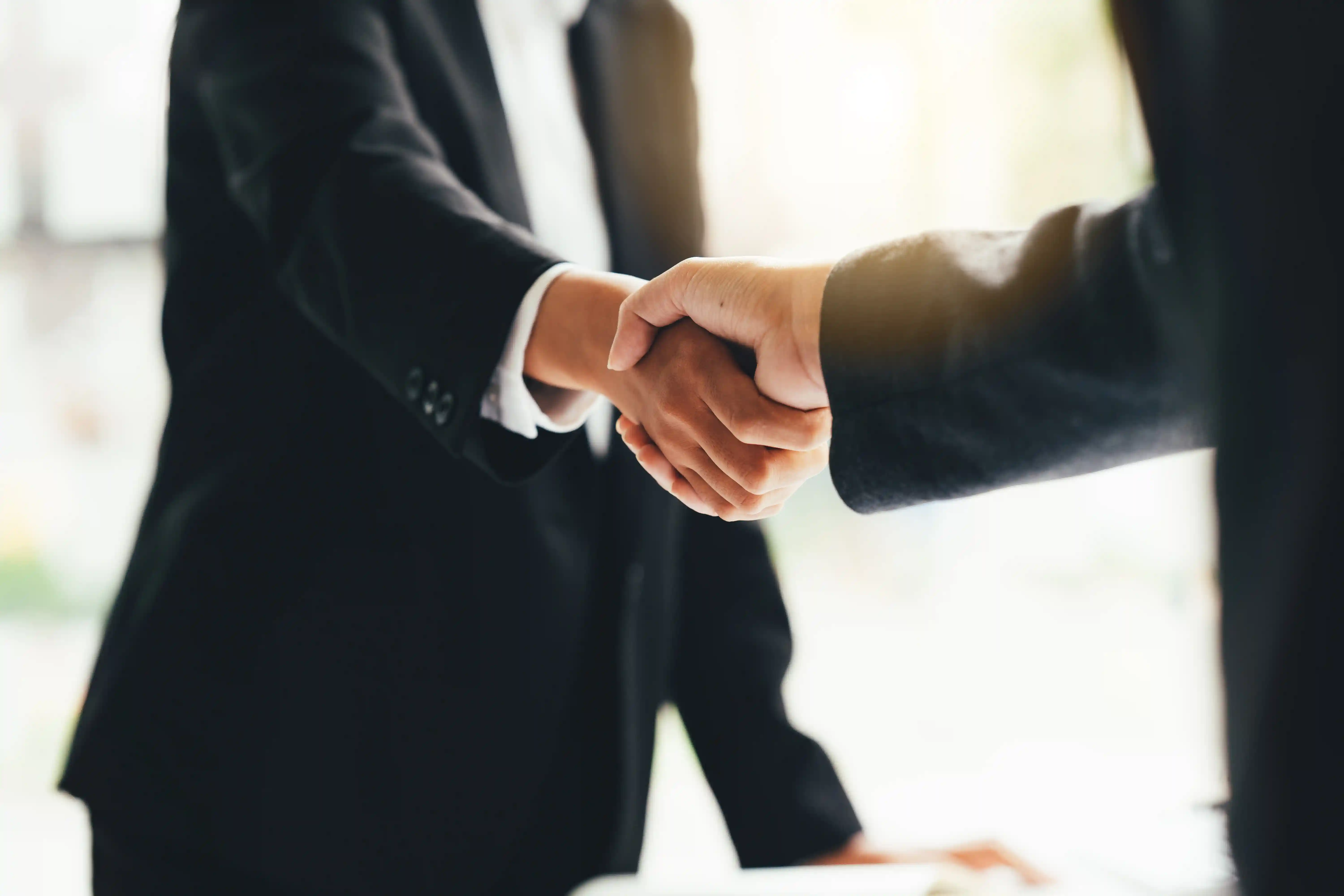 A business owner shakes hands with his insurance agent after securing general liability insurance.